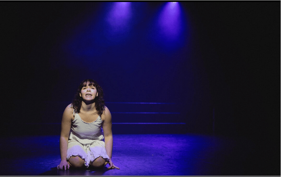Freya Kneels on stage while playing the part of Philomelle