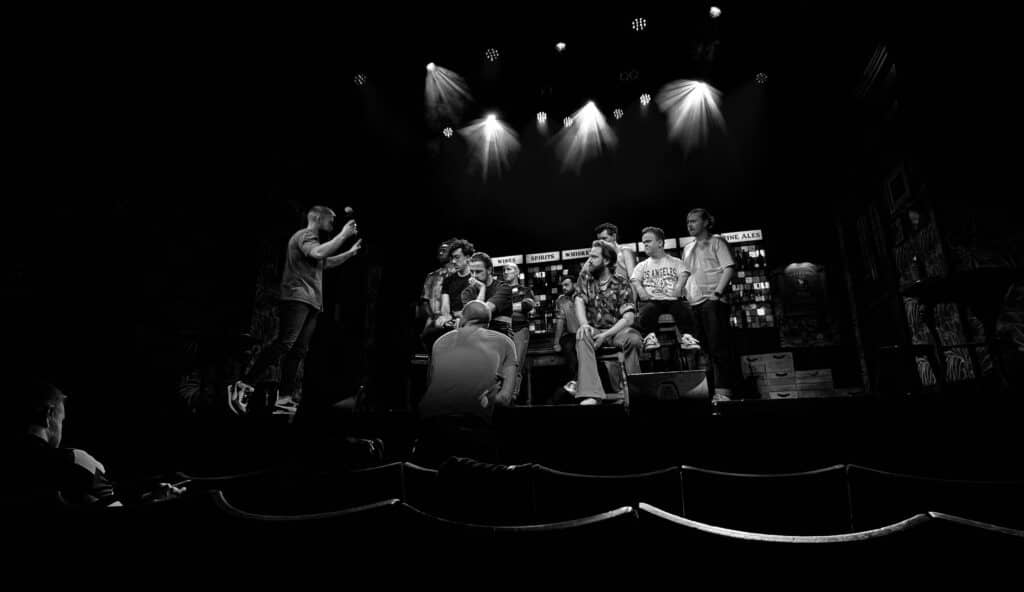adam directs the choir of man cast on stage