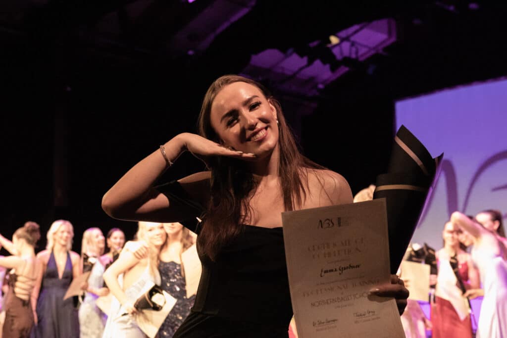 One student playfully posing holding her certificate